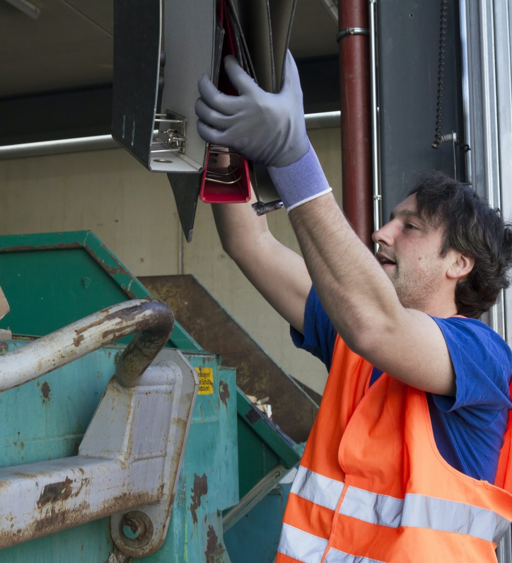 worker-at-a-waste-container-throwing-away-folders.jpg